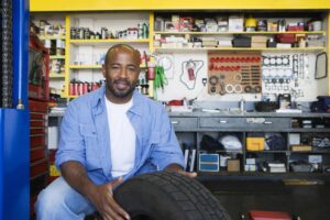 A man inspects his car tyre as part of a regular vehicle inspection (with the help of a vehicle inspection checklist) on a daily, weekly and monthly basis to ensure everything is in working order and to be able to communicate any issues properly with his service plan mechanic.